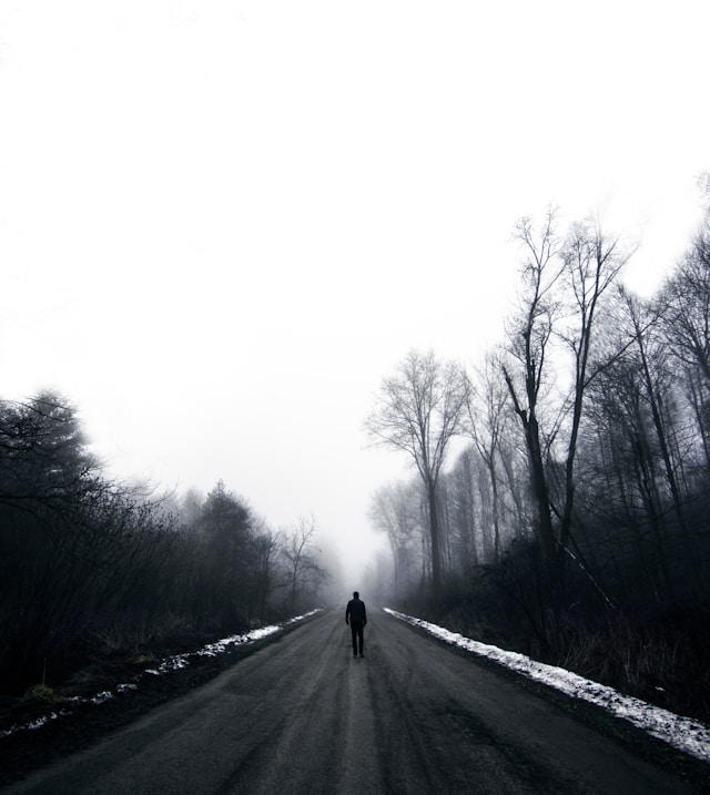man alone walking down road.