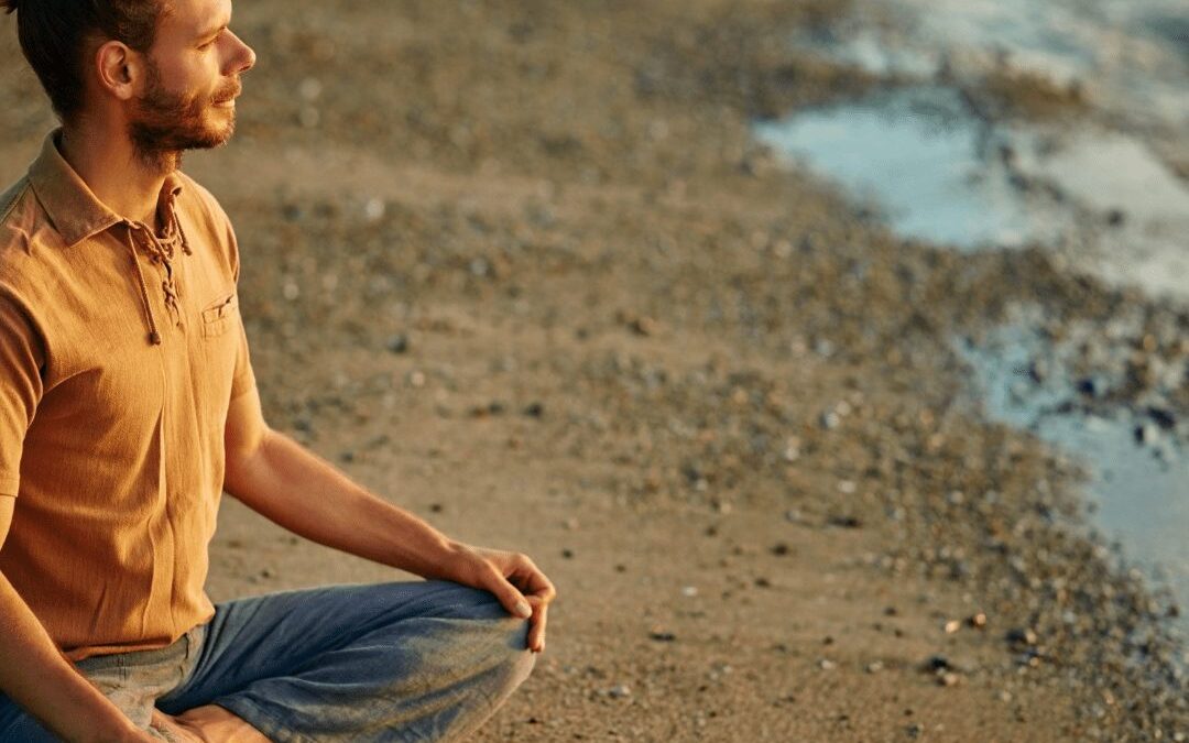 Man sitting cross-legged outdoors by water