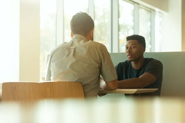 two people sitting at a desk having a conferential conversation.