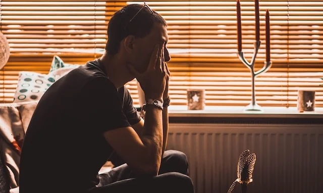 Man sitting indoors with his hand to his face